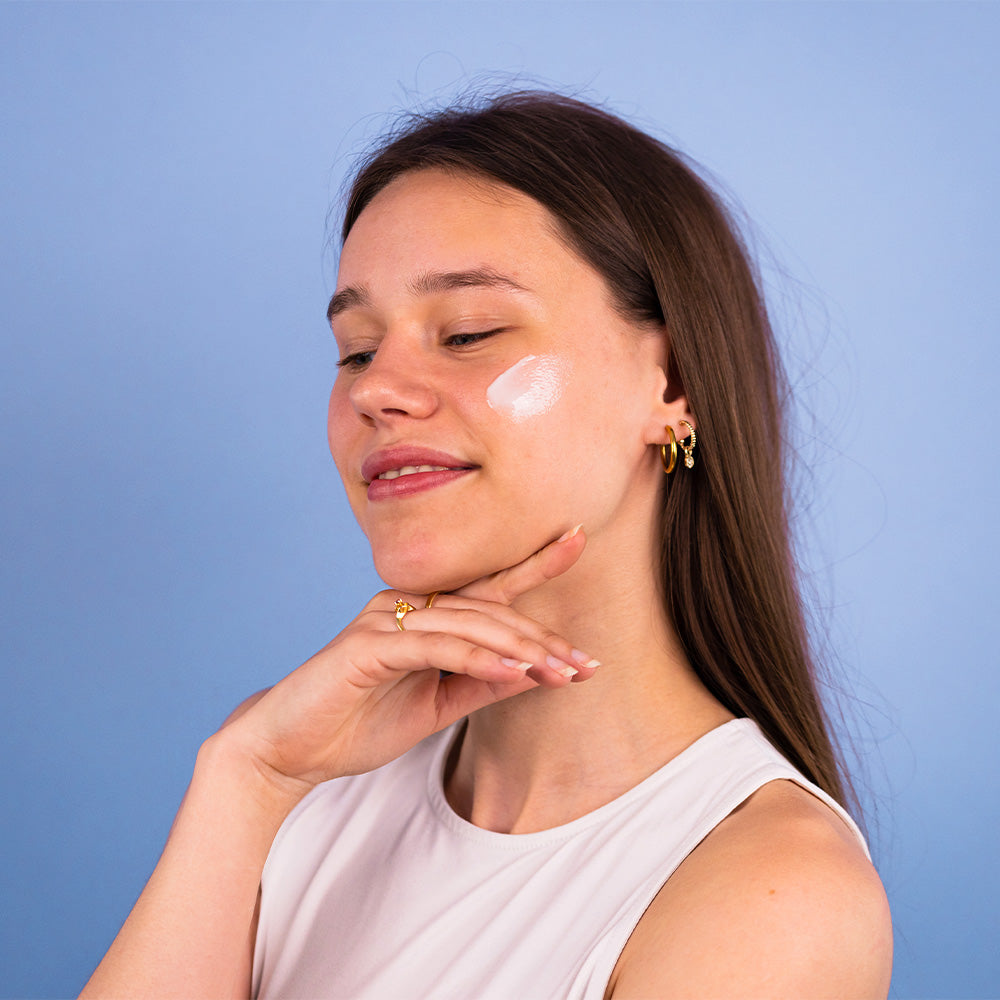 A female with the Collagen Cleansing Milk on their cheek. 